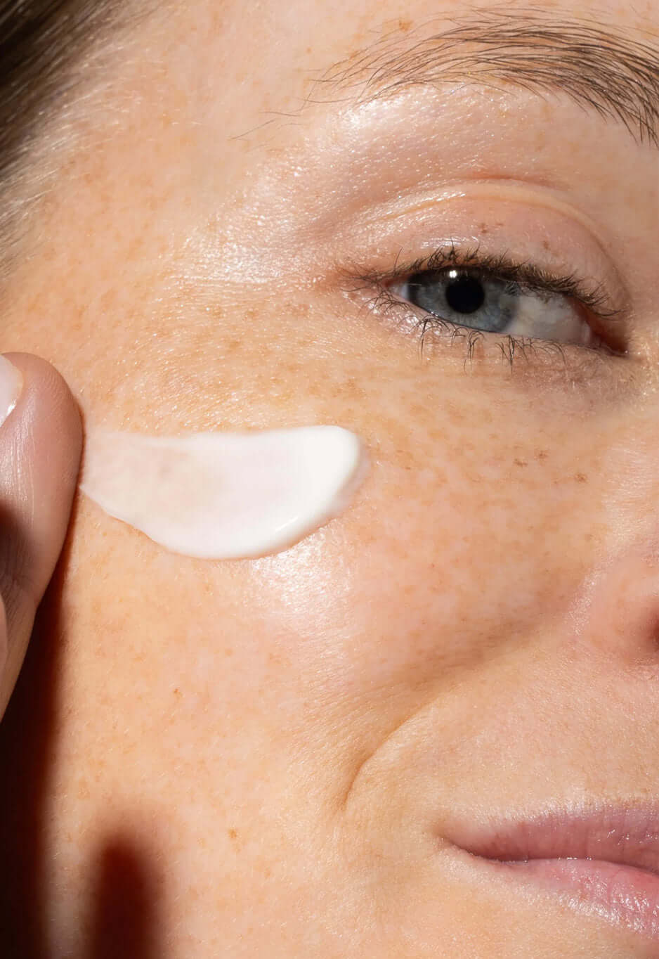 Close-up of a face with a swipe of white cream on the cheekbone below the eye