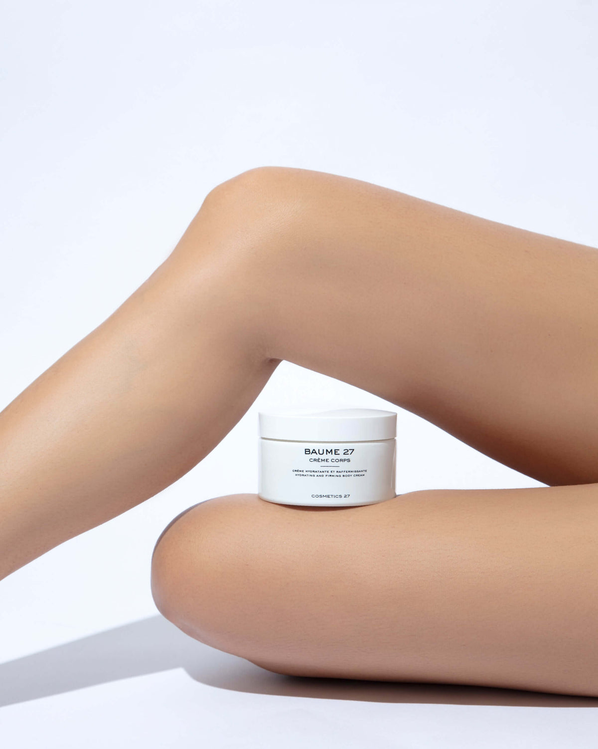 Jar of Baume 27 Body Cream balanced on a bent leg