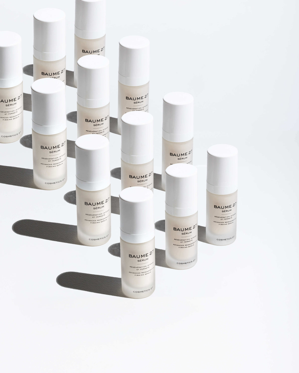Rows of Baume 27 Serum bottles casting shadows on a white background