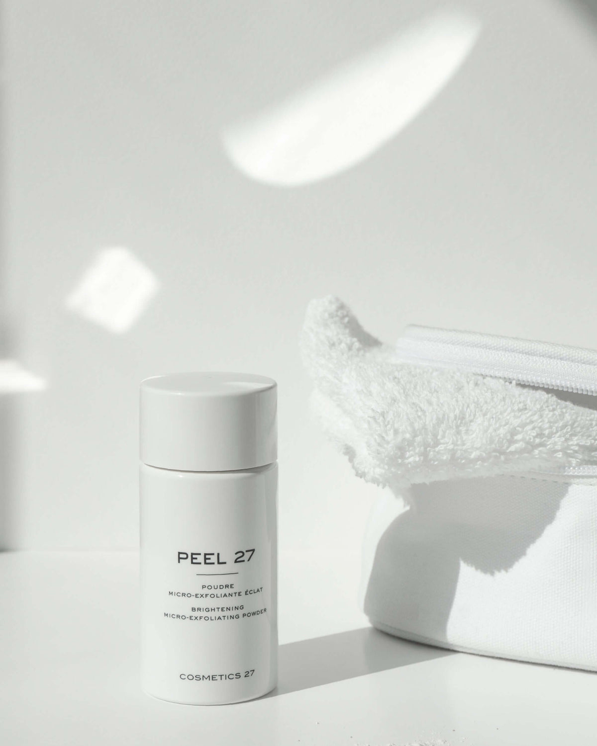 Peel 27 bottle on a white surface beside a pouch and a terry towel