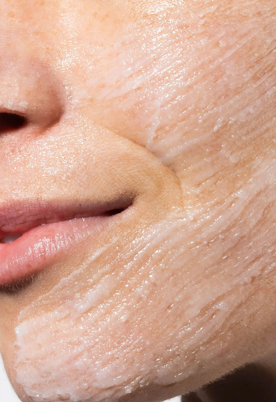 Close-up of a cheek and mouth, the skin covered in white emulsified cleansing balm