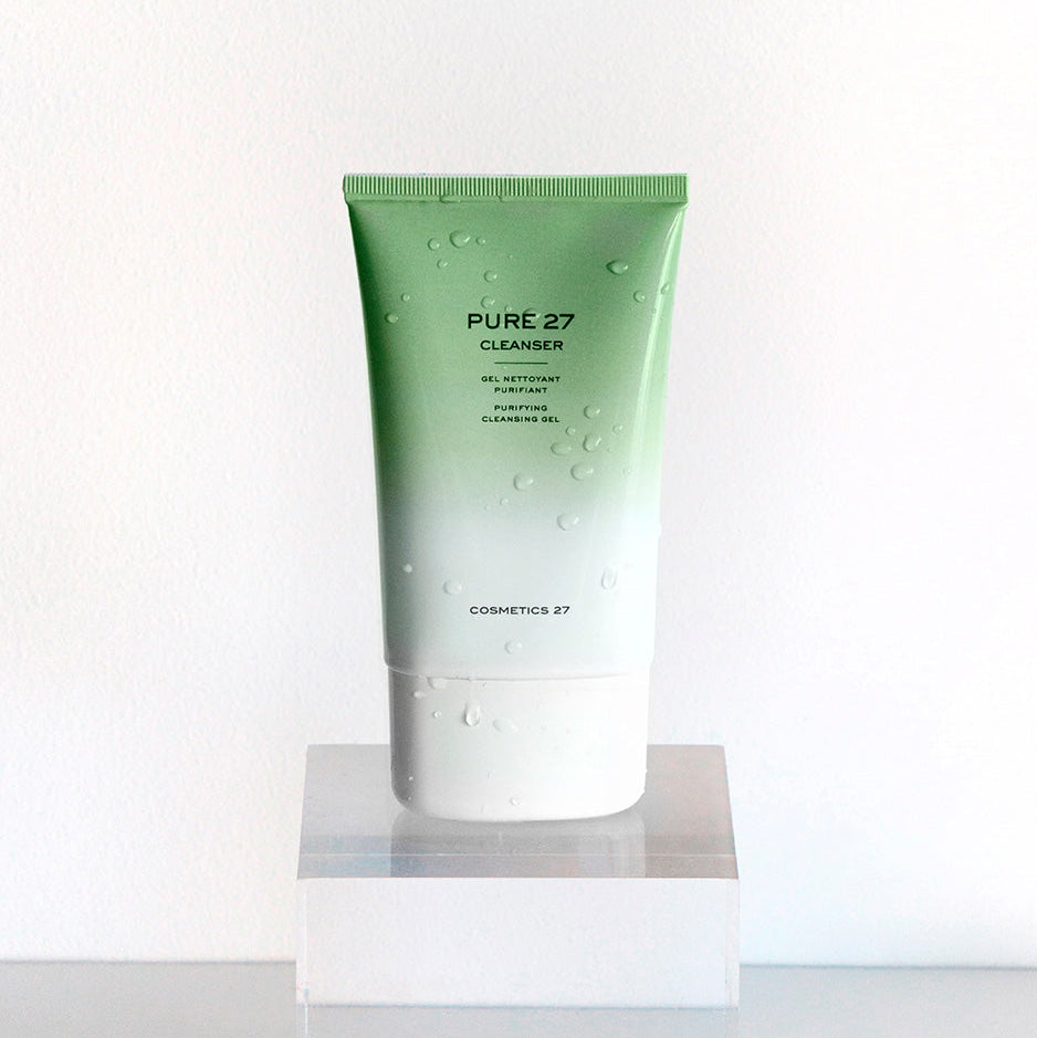 Tube de Pure 27 Cleanser couvert de gouttes d'eau, sur un socle transparent