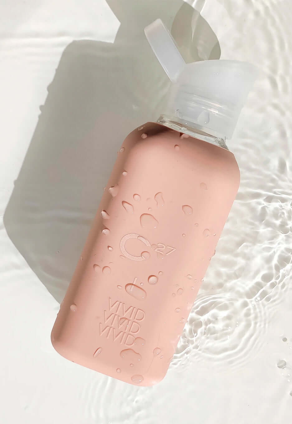 Gourde C27 rose couverte de gouttes d'eau, posée dans l'eau