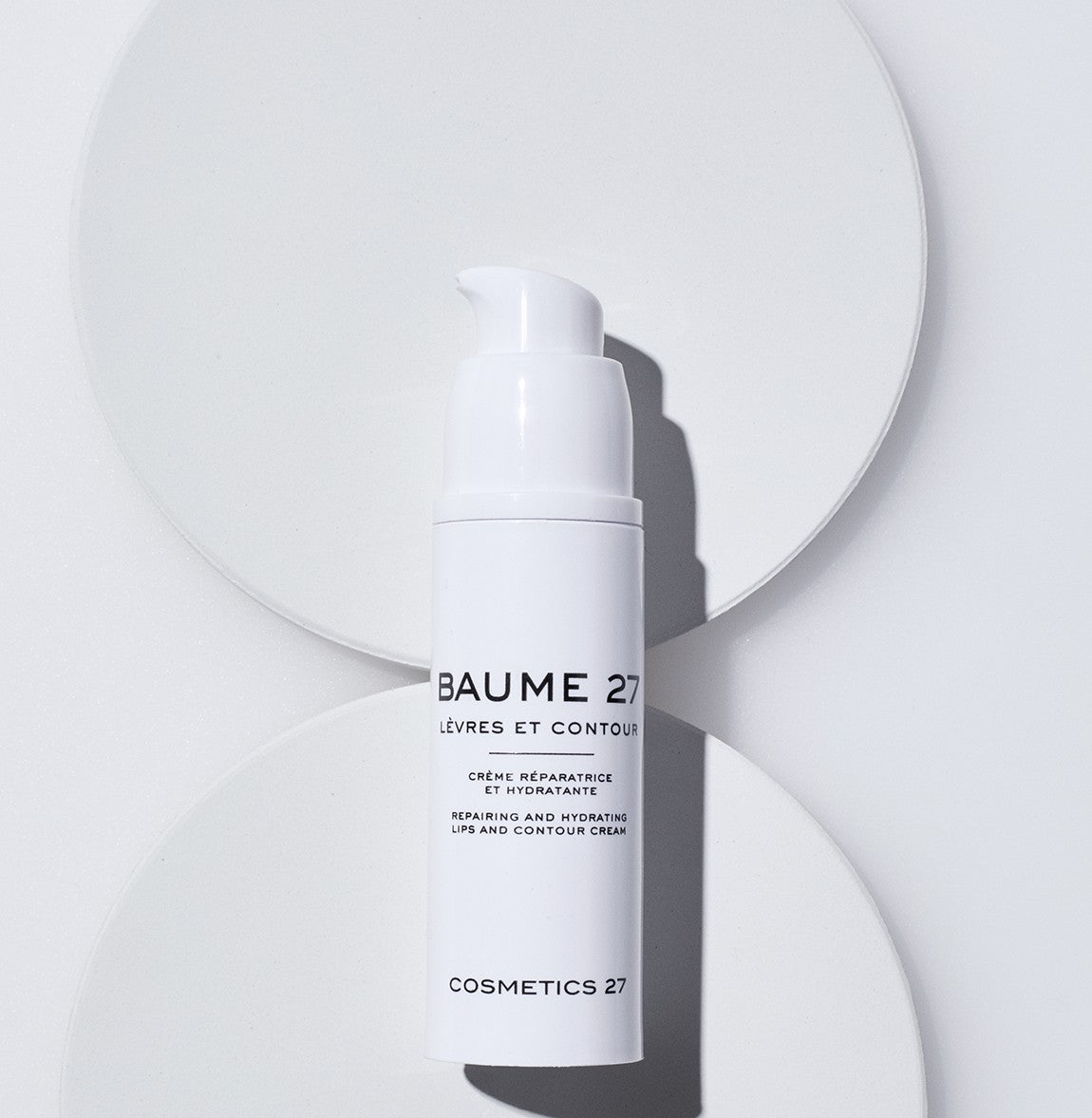 Flacon pompe de Baume 27 Lèvres et contour posé sur deux disques blancs, vue du dessus