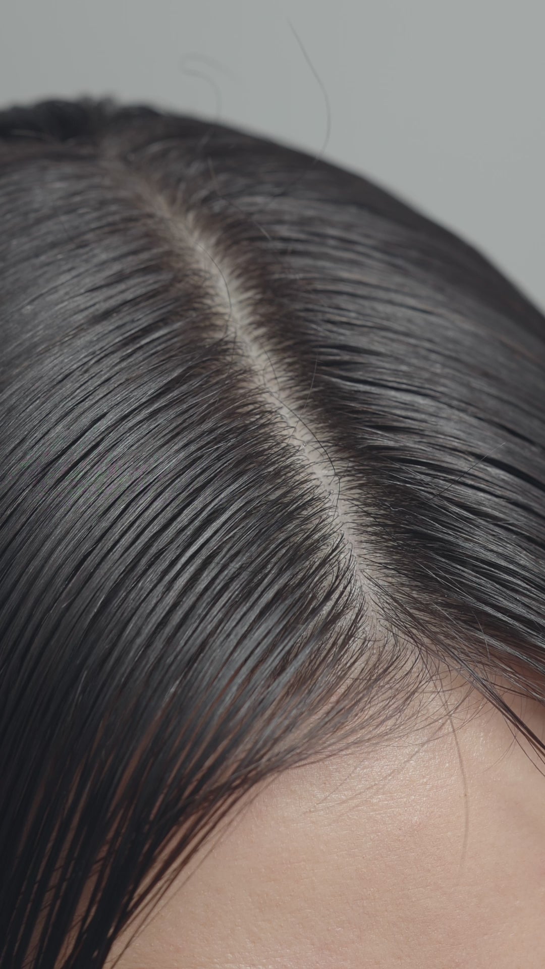 Vidéo : sérum déposé à la pipette sur la raie de cheveux bruns, puis massage du cuir chevelu