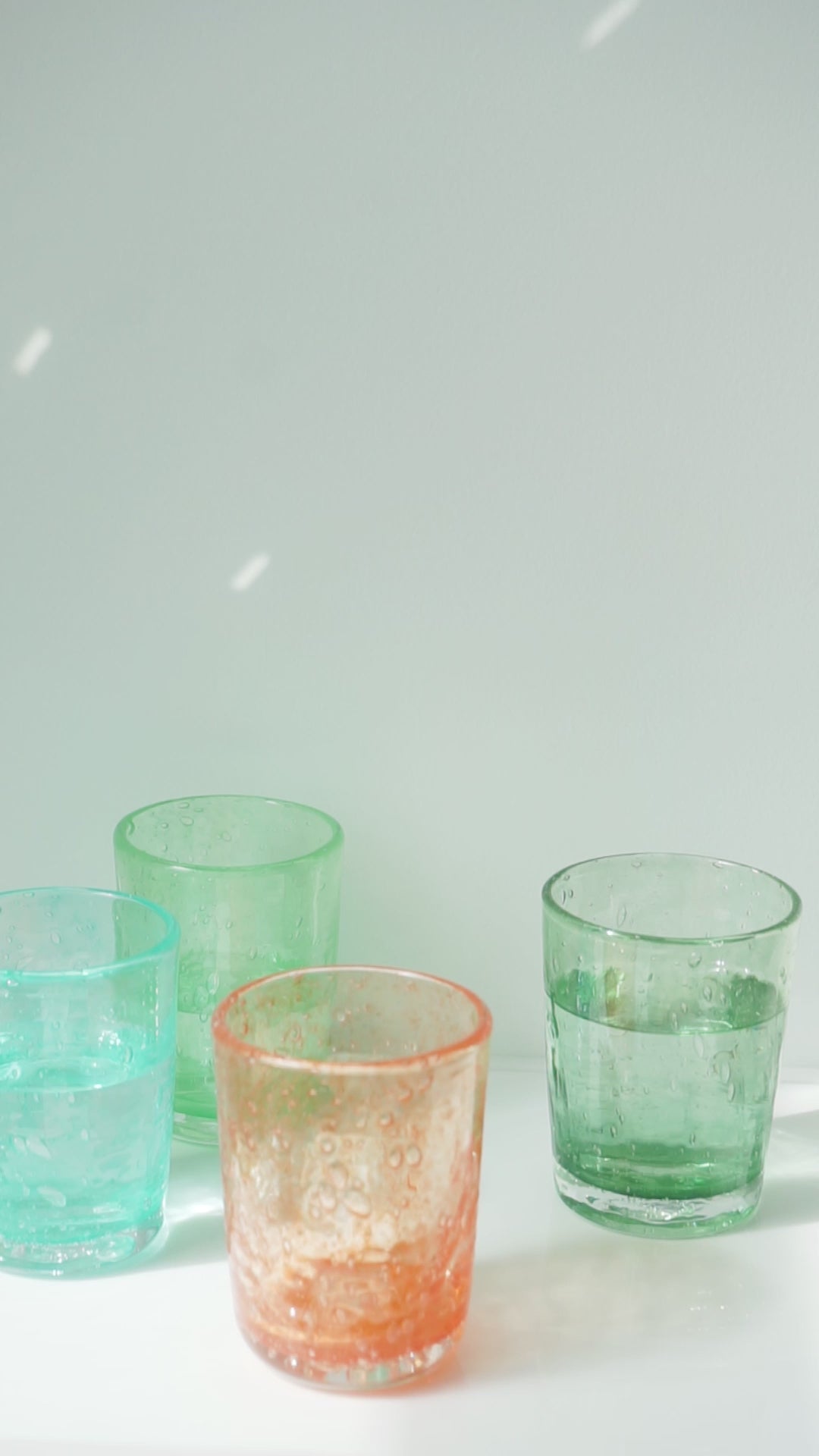 Vidéo : gourde C27 rose versant de l'eau dans un verre, parmi des verres colorés